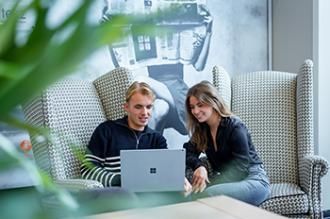 Collega’s overleggen ontspannen met laptop in loungehoek van bluedesk